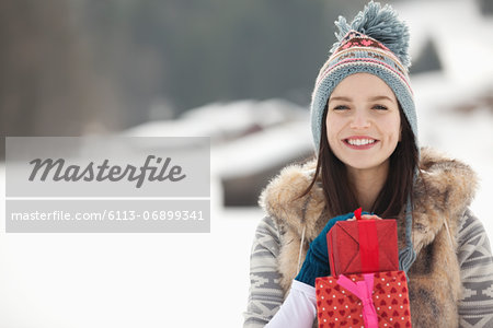Portrait of smiling woman with Christmas gifts in snowy field