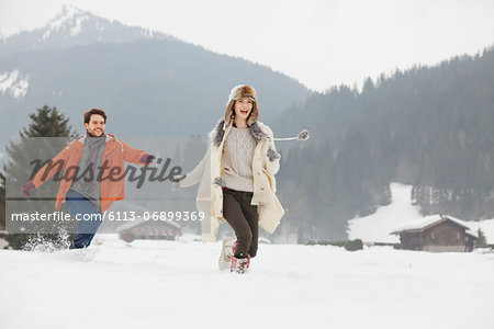 Happy couple running in snowy field
