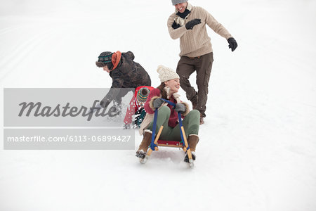 Family sledding in snowy field