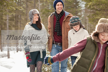 Happy family pulling Christmas tree in snow