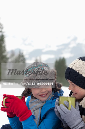 Close up of happy boys drinking hot chocolate in snowy field