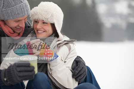 Happy couple drinking coffee in snow
