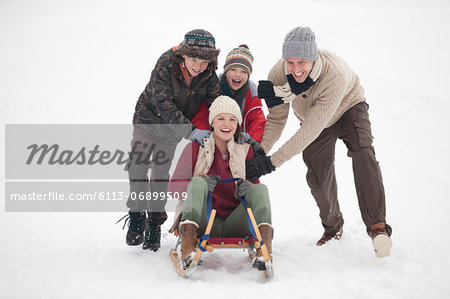 Happy family sledding in snow