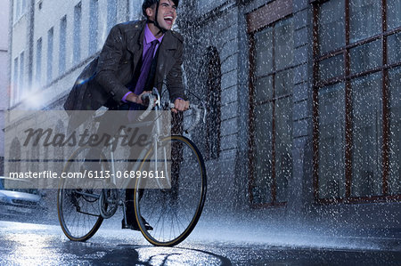 Enthusiastic businessman riding bicycle in rainy street