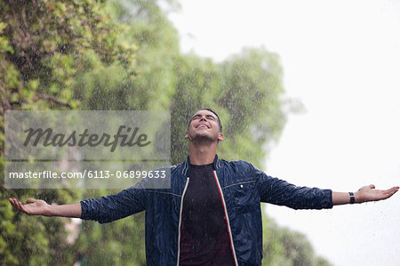 Man with arms outstretched in rain