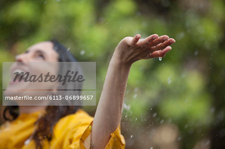 Enthusiastic woman standing with arms outstretched and head back in rain