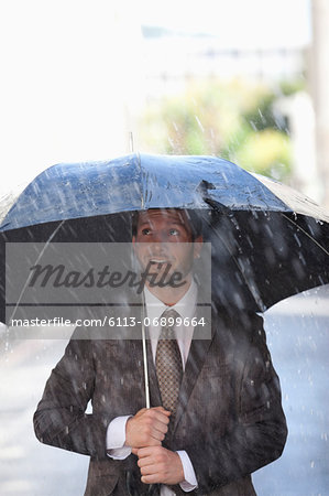 Businessman under umbrella in rain