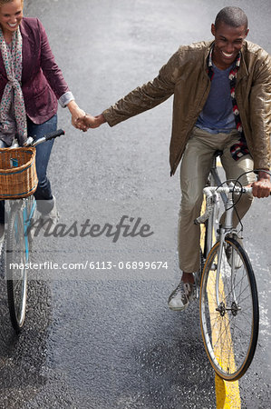 Happy couple holding hands and riding bicycles