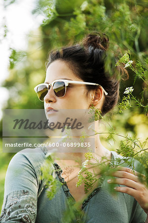 Portrait of teenaged girl outdoors in nature wearing sunglasses, looking into the distance, Germany