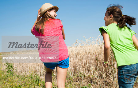 Backview of Girls running in field, Germany