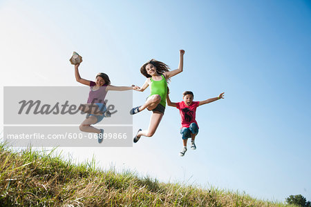 Girls jumping in mid-air over field, Germany