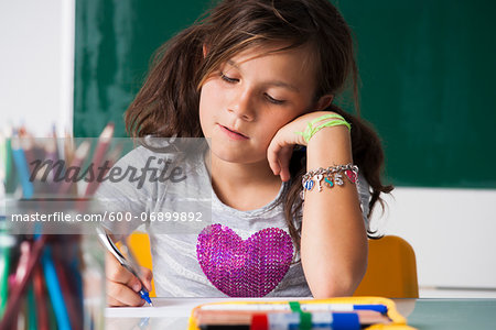 Girl sitting at desk in classroom, Germany