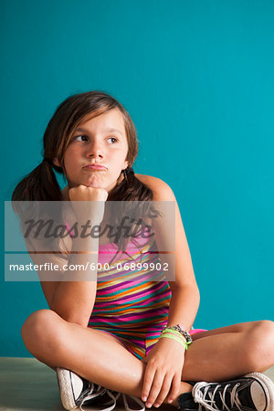 Portrait of girl sitting on floor, pouting, Germany