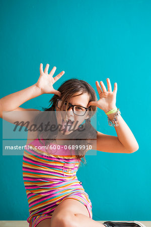 Portrait of girl sitting on floor making funny faces, Germany