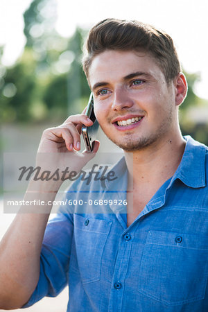 Young man using cell phone outdoors, Germany