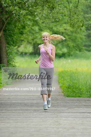 Blond woman running outdoors on wooden footpath, Germany