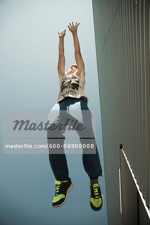 Low angle view of teenager jumping in midair, freerunning, Germany Low angle view of teenager jumping in midair, freerunning, Germany