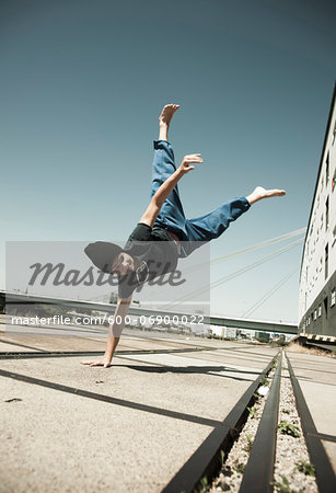 Teenaged boy doing handstand on cement road, freerunning, Germany