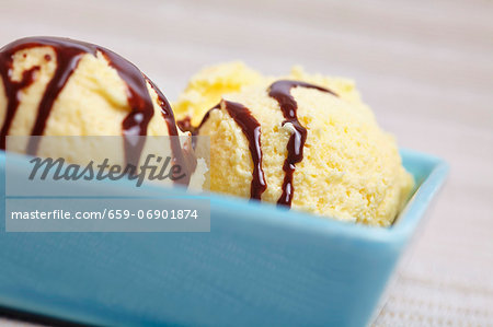 A few scoops of home-made vanilla ice cream with chocolate sauce in a bowl