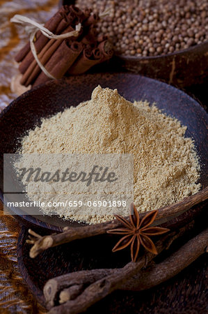 Liquorice root powder in a bowl, surrounded by spices