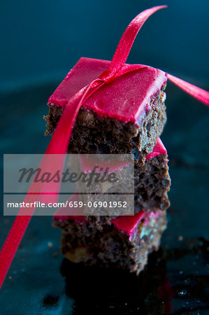A stack of brownies with red icing