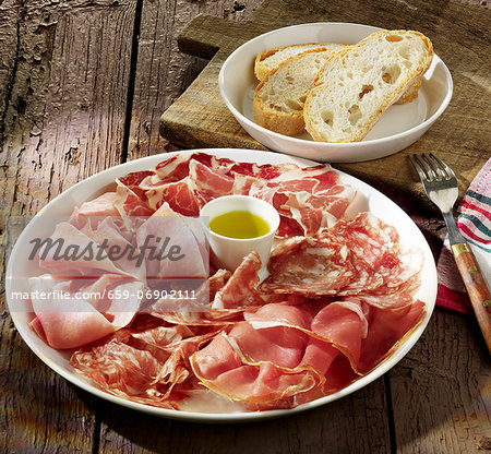 Sausage and ham platter with olive oil and white bread