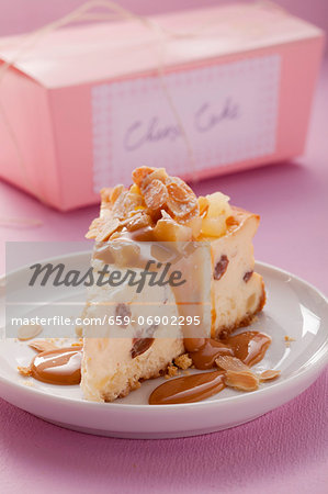 A piece of cheesecake with caramel sauce and slivered almonds