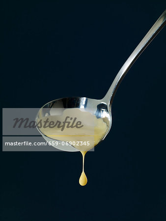 Vanilla sauce dripping from a ladle Vanilla sauce dripping from a ladle