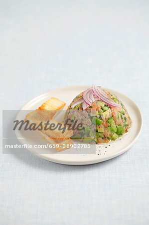 Smoked salmon and avocado tartar topped with onions and served with toast