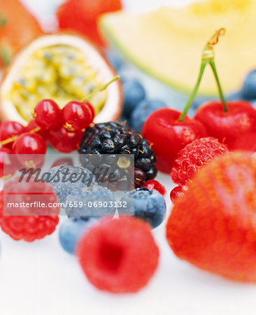 Close up of a selection of fresh fruits including blueberries, redcurrants, passion fruit, raspberries, blackberries, strawberries and cherries.