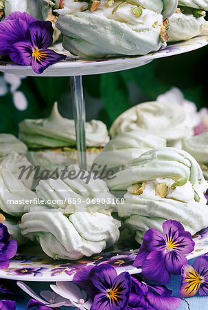 pistacio meringues on a cake stand with pansy flowers