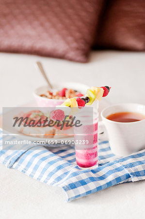 A breakfast tray with a cup of tea and a raspberry smoothie