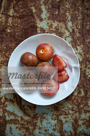 Fresh plums, whole and cut into pieces, on a plate Fresh plums, whole and cut into pieces, on a plate