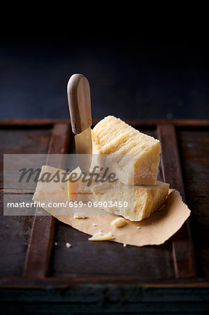 Stacked chunks of parmesan on dry flatbread, with a cheese knife stuck into one of the chunks of cheese