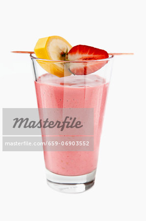 A strawberry smoothie with banana and strawberry pieces on a cocktail stick