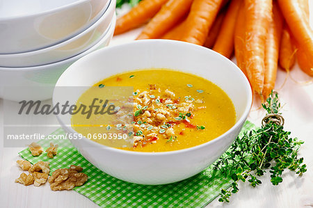 Celery and carrot soup garnished with fried celery, bell pepper, walnuts and thyme; selective focus