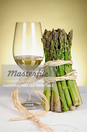 Glass of white wine and green asparagus tied together