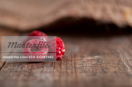 Three frozen raspberries on a rustic surface