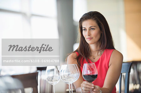 Woman holding a wine glass and thinking in a restaurant