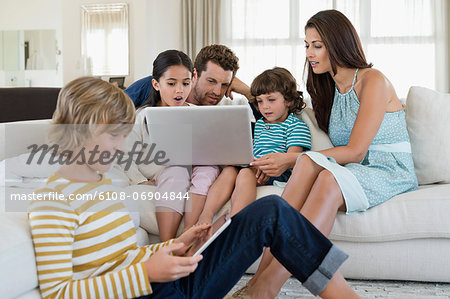 Family using electronic gadgets in a living room Family using electronic gadgets in a living room