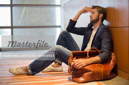 Man leaning against a wall at an airport