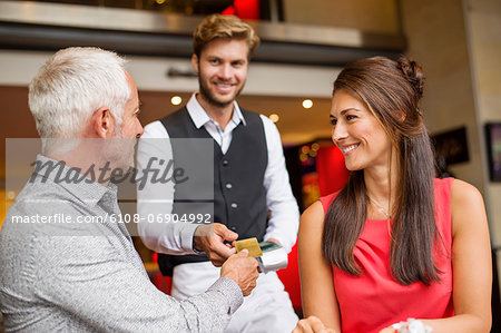 Couple paying with a credit card to a waiter in a restaurant