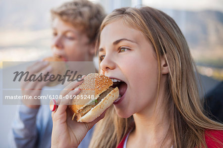 Close-up of two friends eating hamburger Close-up of two friends eating hamburger