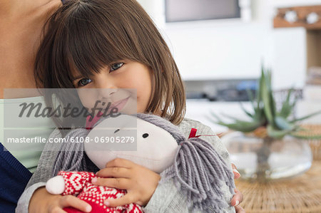 Close-up of a girl sitting with her mother and holding a rag doll Close-up of a girl sitting with her mother and holding a rag doll