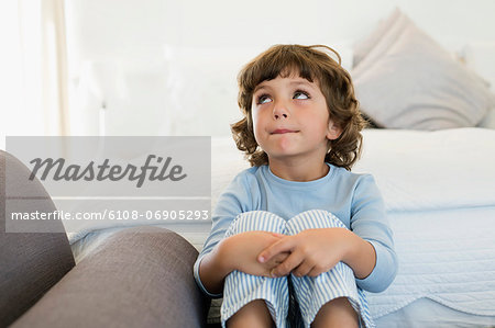 Boy sitting on the bed looking up