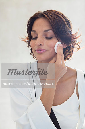 Woman cleaning her face with a cotton pad