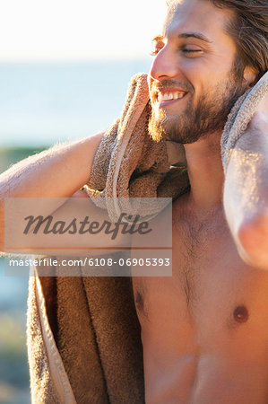 Happy man wiping himself with a towel on the beach