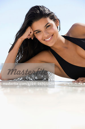 Beautiful woman lying on the beach and smiling