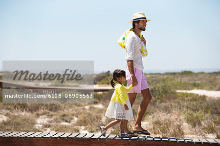 Man with his daughter walking on a boardwalk on the beach