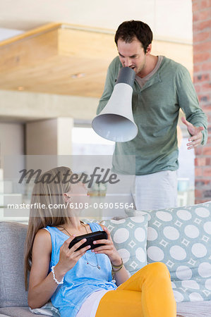 Man shouting into a megaphone at his daughter for playing video game